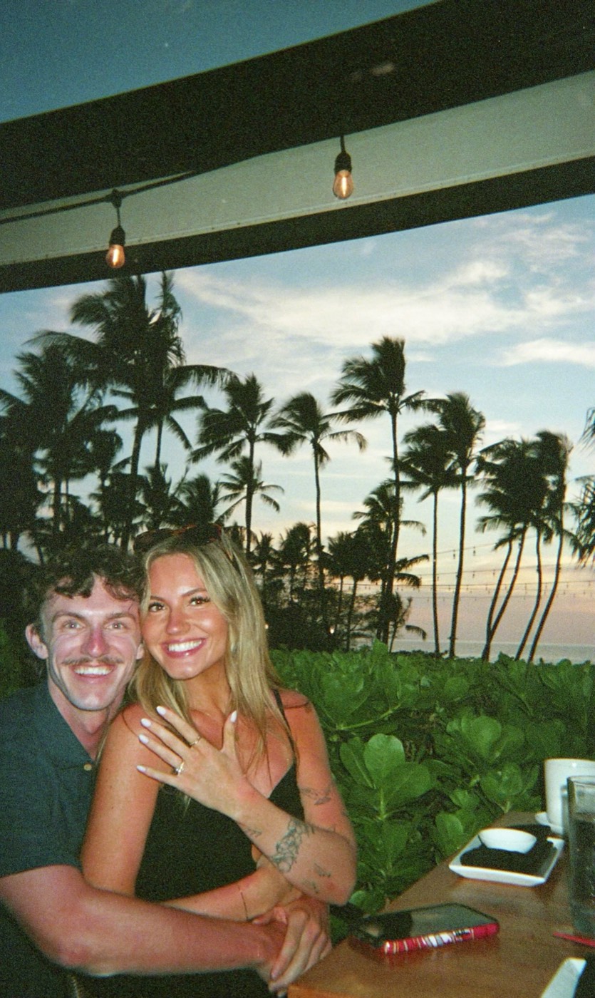 Cole and his fiancée at dinner by the ocean at sunset