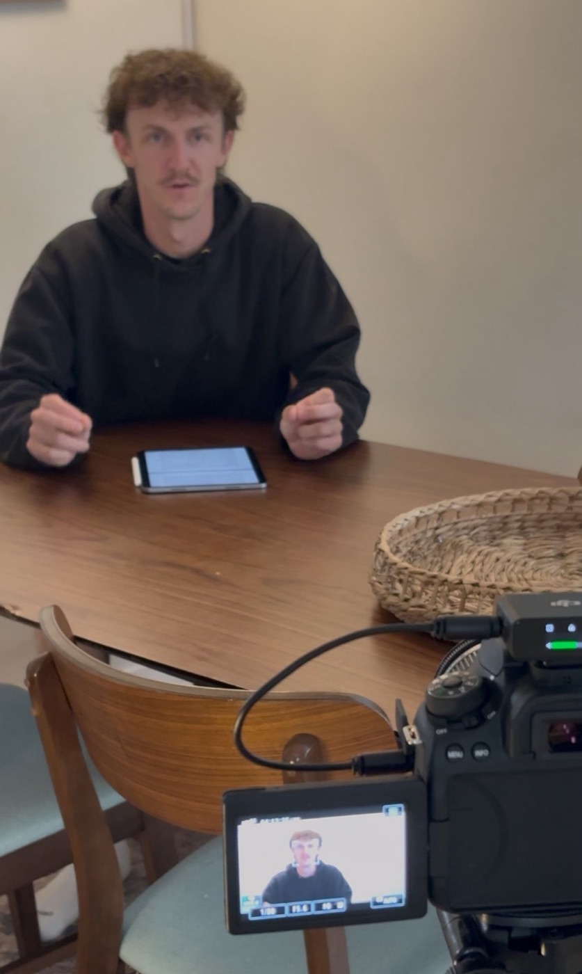 Cole at a table, recording a lesson on camera